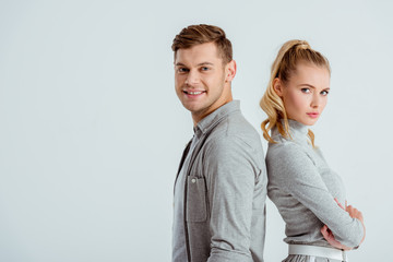serious woman and handsome smiling man posing together isolated on grey