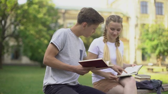 Two teenagers reading books in park, preparing for examination, studying