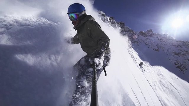 Person snowboarder snowboarding down slope closeup with gopro