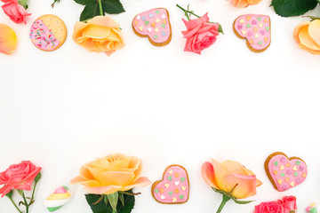 Frame of roses flowers with cookies on white background. Flat lay