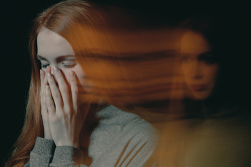 Blurred picture of young beautiful redhead girl with obsessive compulsive disorder covering her mouth and closing her eyes - obrazy, fototapety, plakaty