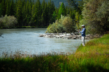 Fototapeta na wymiar Young adult angler fishing on the river. Altai, Russia