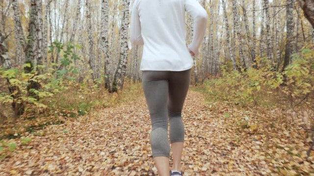 Young blonde woman running in the autumn park.