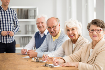Happy group of elderly people with teacher before exam at third age university