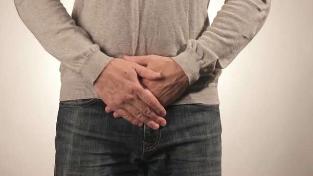 Man covering his urethra in pain. Men problems on white background. Medical concept