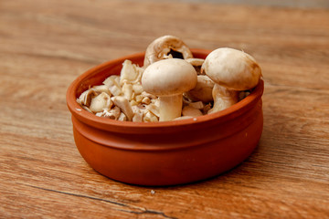 Fresh white champignon mushrooms in brown ceramic bowl on wooden vintage table