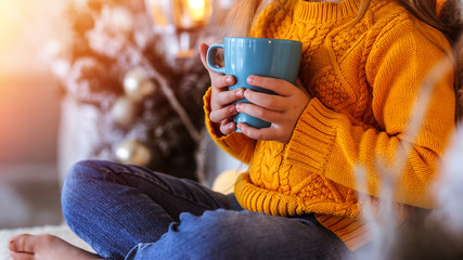Girl with a cup on the background of the Christmas tree.