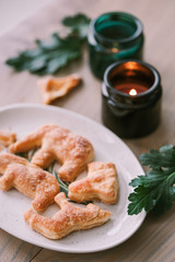 Homemade shaped cookies on a wooden table next to candles and green leaves. The concept of Christmas atmosphere and comfort.