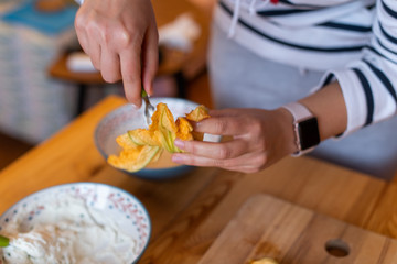 Preparing zucchini flowers stuffed with ricotta cheese, woman's hand shown