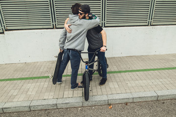 Young people riding bikes and skateboards in the city. Guys with a skate and a bmx down the street.