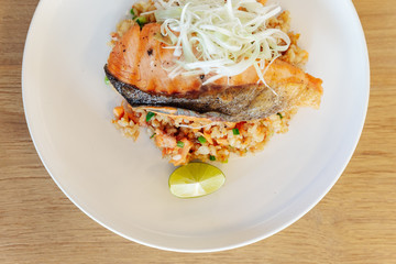 Top view of Garlic fried rice with grilled salmon served with chili bean sauce on wooden background.