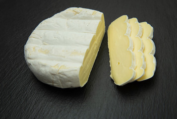 Camembert. Soft creamy cheese sliced on dark background