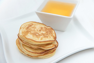 Pancakes and honey. In white porcelain plates