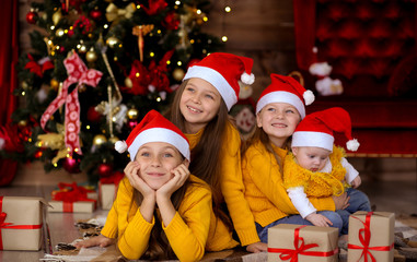 Children smiling in red hats on the background of the Christmas tree