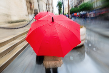 person with red umbrella in the rainy city with zoom effect