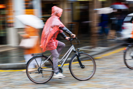 Fototapeta person with rain cape riding a bicycle