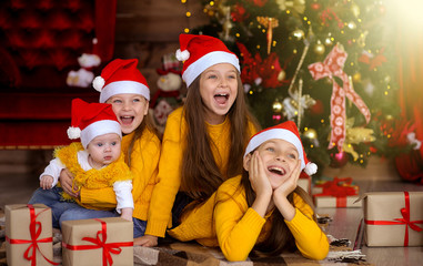 Children smiling in red hats on the background of the Christmas tree