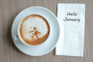 Hello January word with hot cappuccino coffee cup on table background at the morning. New Year New Start, Resolution, Solution, Strategy and Mission concept