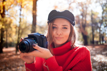 Young woman having fun with camera making photos at green park