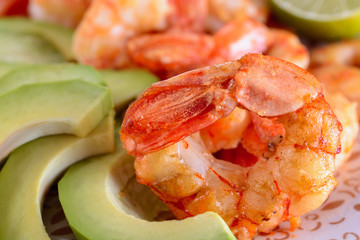 Grilled shrimps next to fresh avocado slices close up