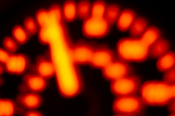 A Defocussed car speedometer lit up by orange light at night