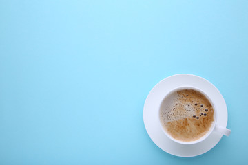 Cup of coffee on blue background, flat lay