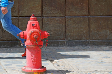 Red fire extinguisher on the footpath with a man walking behind, Puno old town, Peru, South America 