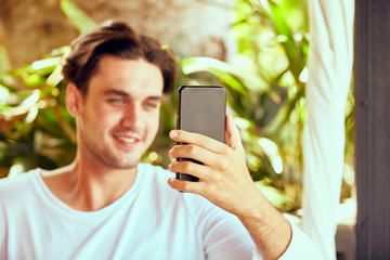 Man using cellphone while working on laptop outdoors.