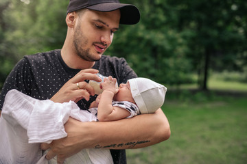 Father standing outside feeding his baby boy with a bottle