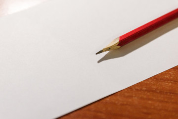 A simple pencil lies on a white piece of paper. Pencil and paper for notes.