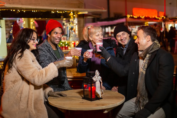 Group of friends laughing and cheering at Christmas market.
