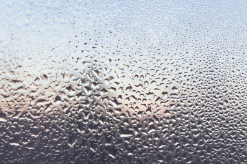 The frozen drops on the patterned frosty winter window