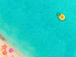 Aerial view of woman floating on inflatable mattress by sandy beach.
