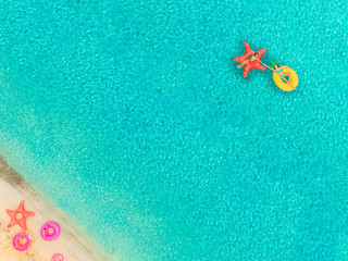 Aerial view of two girls floating by beach on inflatable mattress holding hands.