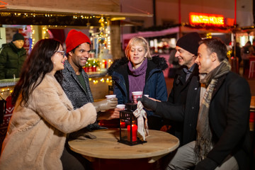 Group of friends cheering with traditional drink at Christmas market.