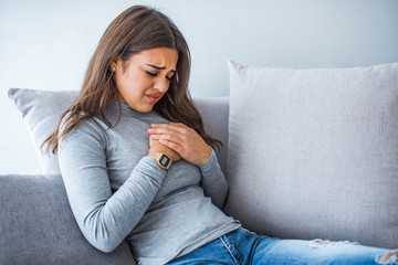 Depressed young woman on light background