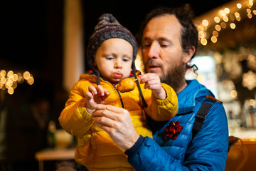 Fototapeta na wymiar Portrait of father holding son at Christmas market in Zagreb, Croatia.