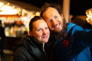 Fototapeta premium Portrait of couple taking selfie, traditional Christmas market, Zagreb, Croatia.