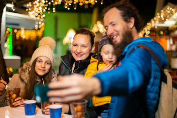 Father taking selfie with family at traditional Christmas market.