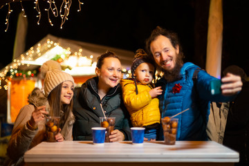 Father taking selfie with family at traditional Christmas market.