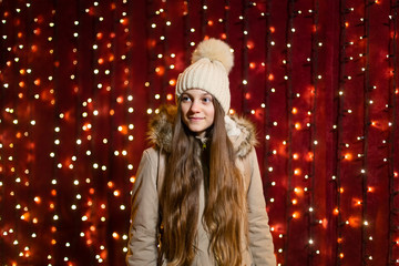 Teenager with long hair posing in front of lights wall at Christmas market.