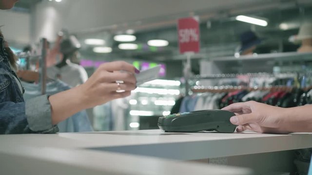 Woman paying using payment card. The seller gives and removes the payment terminal and gives purchases. Hands close up view