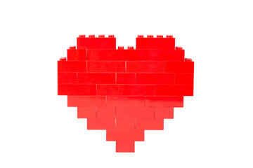 Fototapeta premium Red heart made of toy building bricks, viewed from the front. Isolated on white background.