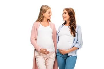 Naklejka premium two pregnant adult women smiling each other isolated on white