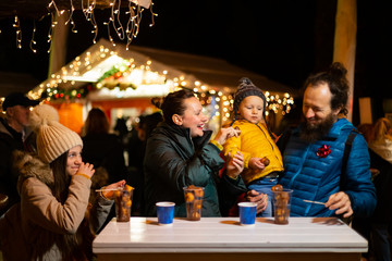 Family enjoying traditional food at Christmas market in Zagreb, Croatia.