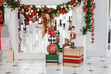 Christmas tree decorated in interior with armchair, candles, nutcracker, presents.