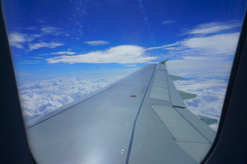 Fototapeta na wymiar Airplane wing in the sky. View from airplane porthole. Beautiful blue sky with clouds
