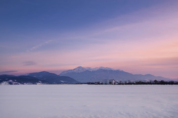 Majestic, beautiful sunset in mountains, Stunning winter landscape with snow covered hills at horizon. Concept of holidays at ski resort. 
