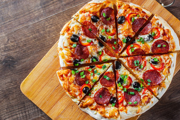Pizza with Mozzarella cheese, pepperoni, tomato, pepper, olive, salami. Italian pizza on wooden table background