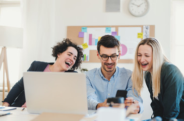 Group of young businesspeople with laptop working together in a modern office.